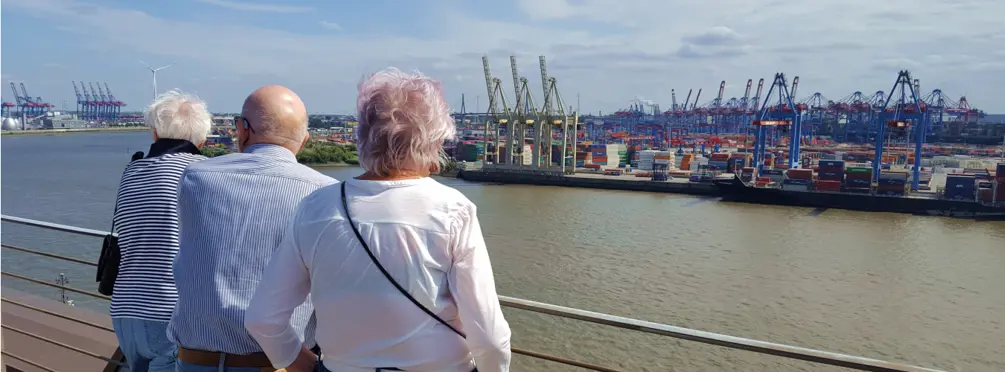 Drei ältere Menschen schauen auf Containerhafen in Hamburg