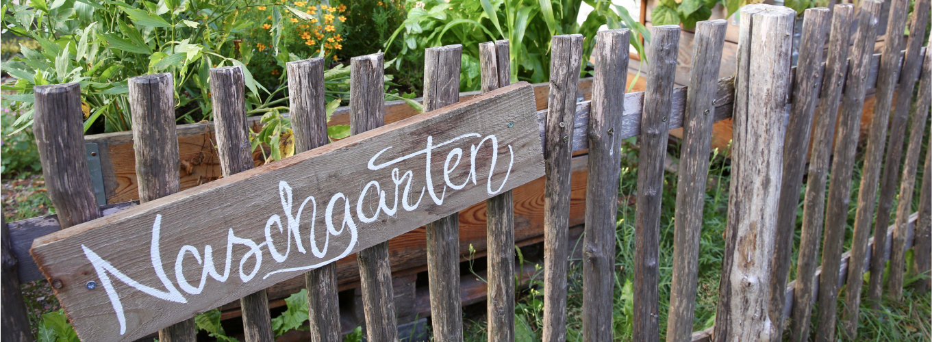 Ein Holzzaun mit einem Schild auf dem Naschgarten steht